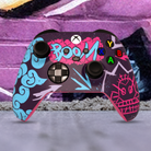 "Custom Arcane inspired Xbox Series X controller with vibrant graffiti art design, featuring bright blue, pink, and purple street-style graphics with 'BOOM' text on the touchpad, displayed in front of an urban graffiti wall."